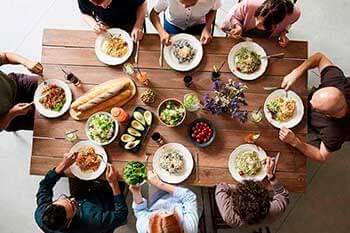 Personas sentadas en la mesa y comiendo abundante comida
